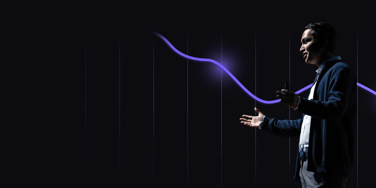 Business leader giving a presentation in front of a glowing purple upward-trending line chart on a dark background.