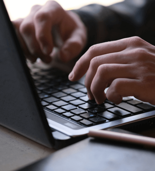 A set of men's hands working on a laptop.